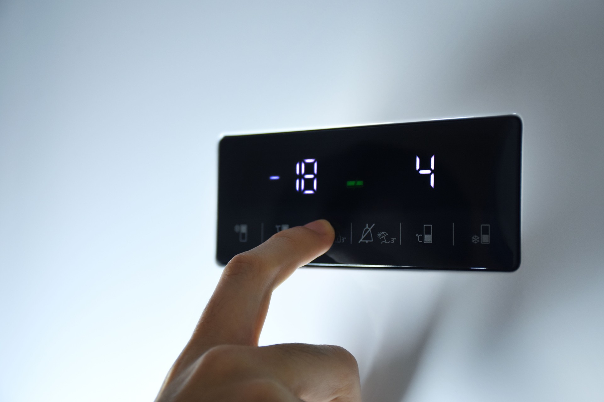Hand adjusting the temperature of the refrigerator
